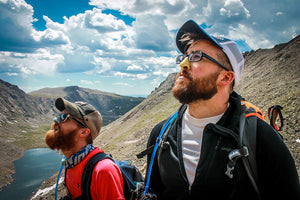 Two men exploring nature while wearing cool and colorful sunscreen protection on their noses.